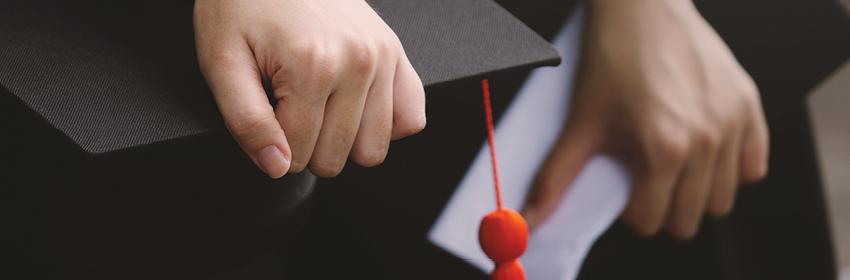 Close up of student hand holding graduation hat.