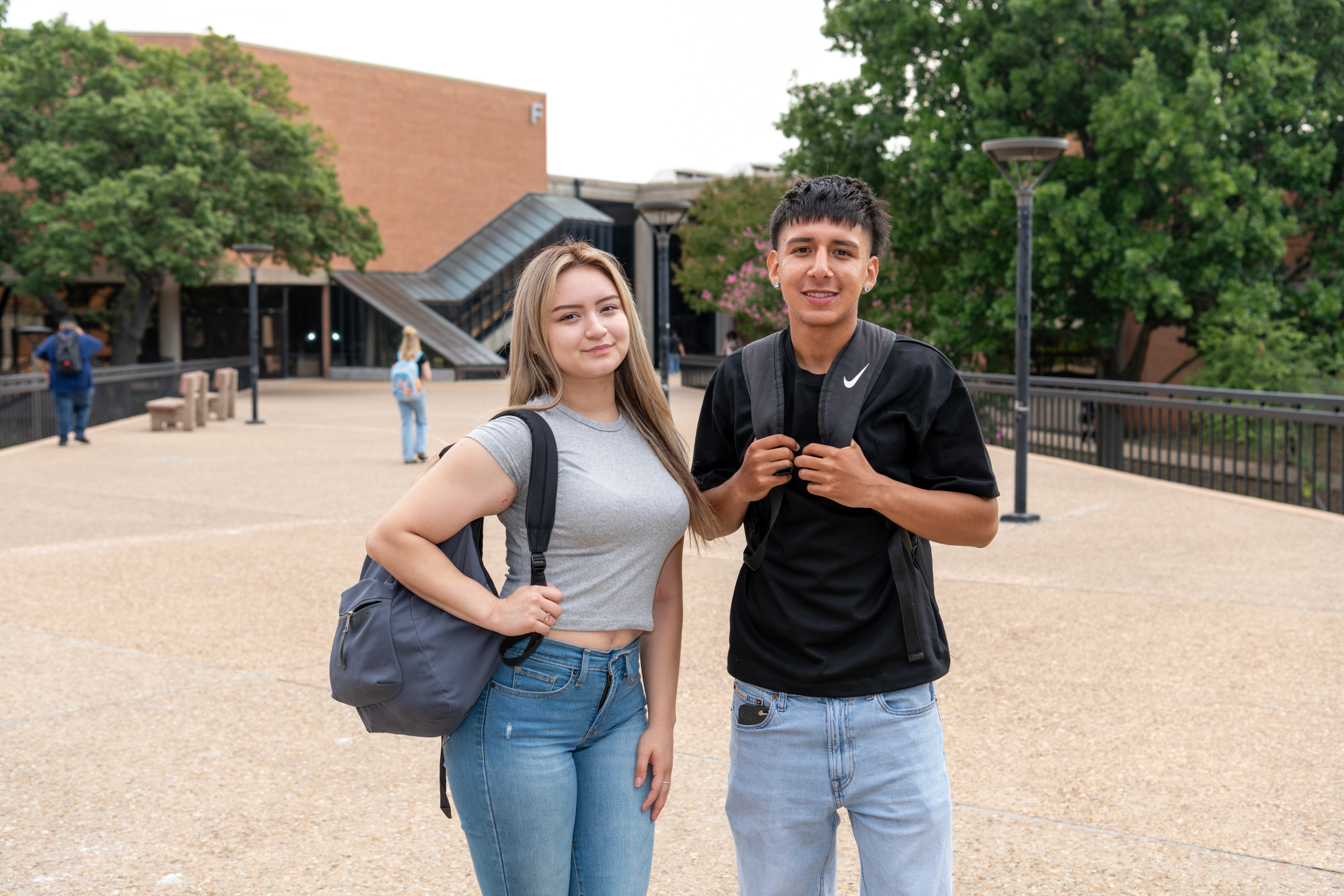 Two students on Dallas College campus standing outside in front of building